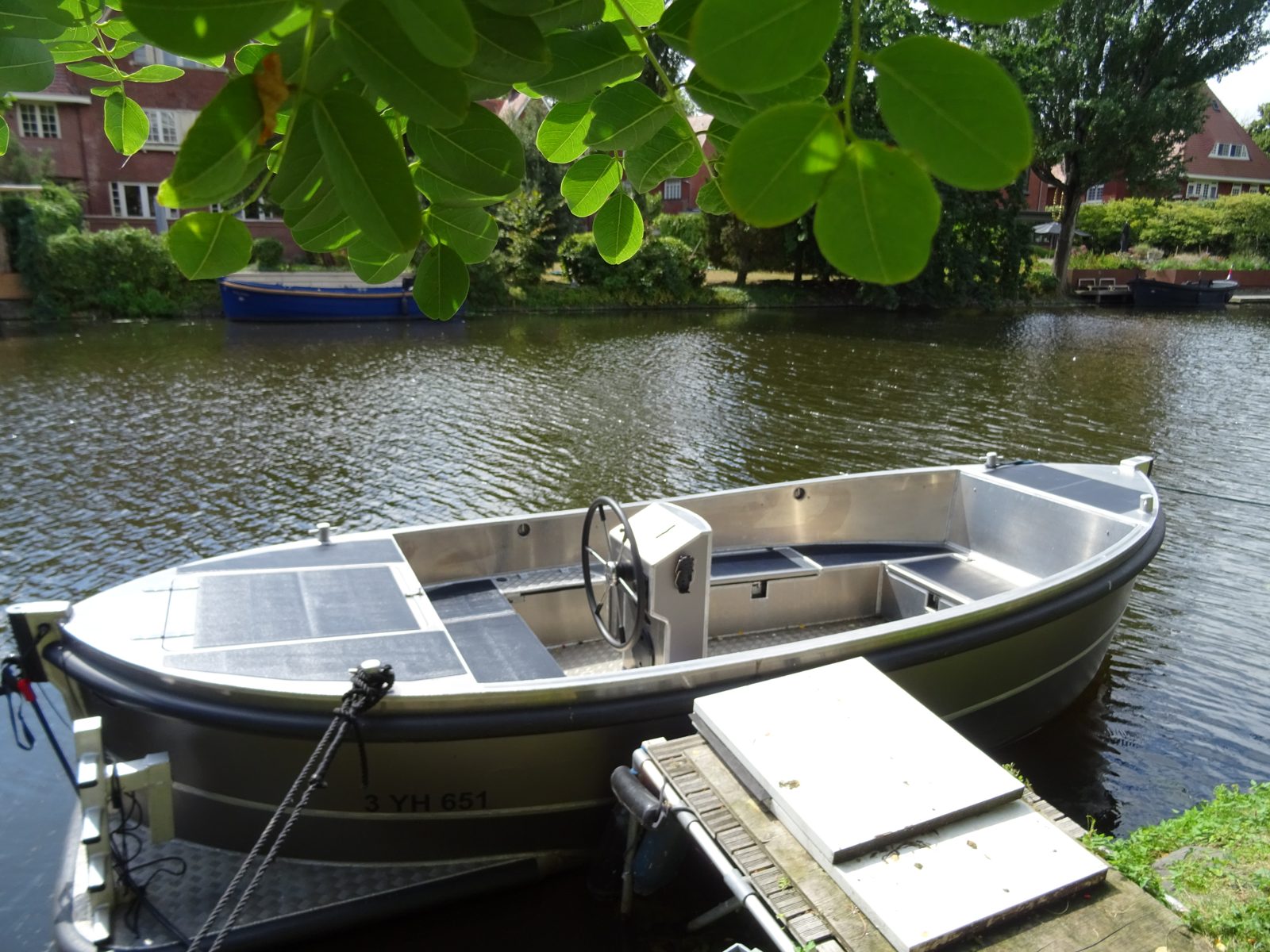 Omgebouwde aluminium sloep met zonnepanelen aan de kade